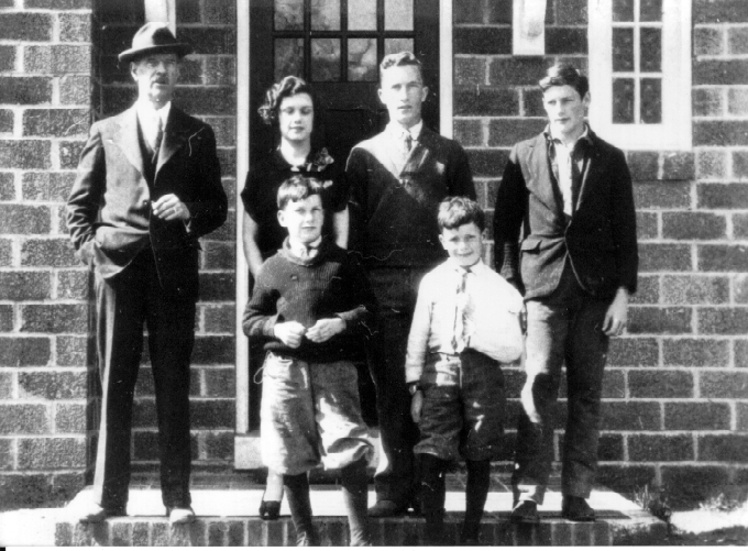 A family portrait of the Owens family, taken around 1930, in front of the door to their brick home on Taney Avenue in Annapolis, Maryland. Pictured from left to right are Norman, Billy, Chuck, Jack, Molly, and Charles Owens.