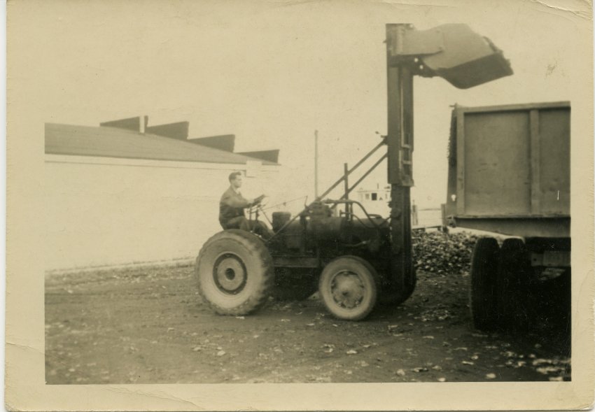 A worker uses a lift to load shells into the back of a truck behind McNasby's.