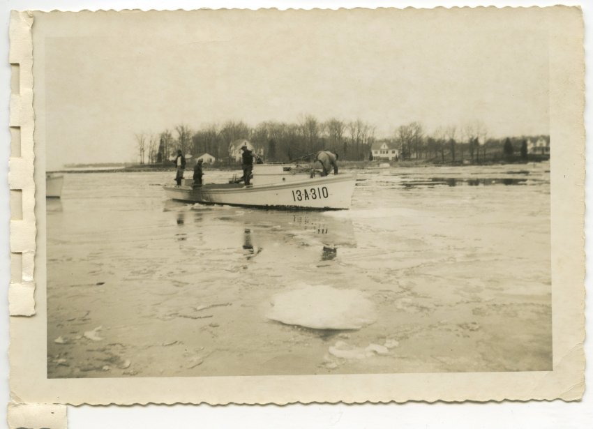 Four watermen make their way through the creek by breaking apart the ice.